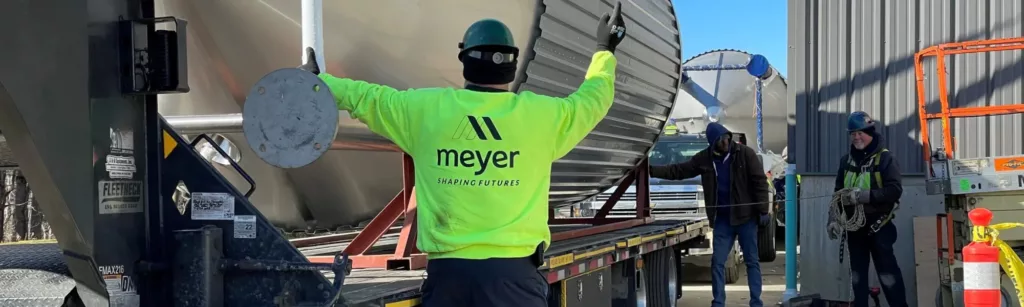 Meyer inc staff member directing a truck transporting heavy equipment