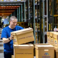 Employee handling boxed paper records inside a secure document shredding facility